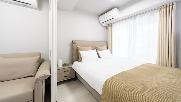 Ein modernes Hotelzimmer mit Bett, Sofa, Nachttisch und Klimaanlage.