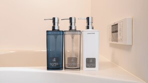 Drei Flaschen Duschgel, Shampoo und Conditioner auf einem weißen Regal.