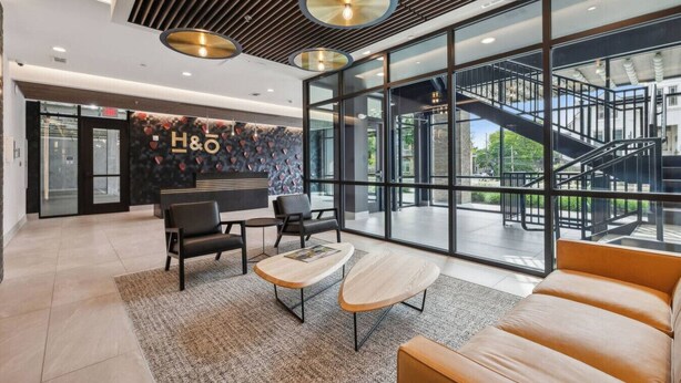 A modern hotel lobby with a reception desk, seating area, and large windows offering views of the outdoors. - The Sound Wave Luxury Condo Near Vanderbilt on Music Row, Just Minutes to Broadway (Nashville)