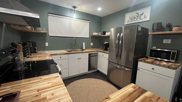 A compact kitchen with a stainless steel refrigerator, a microwave, and a sink. - Charming Eastham Guesthouse (Charlottesville)