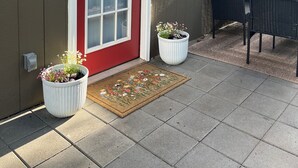 A house with a red door, a porch with two potted plants, and a table and chairs. - Charming Eastham Guesthouse (Charlottesville)