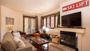A living room with a sofa, armchair, coffee table, fireplace, TV, and a 'Ski Lift' sign. - Kendall 231 - Managed by Purgatory Resort (Durango)