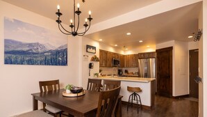 A modern kitchen with wooden cabinets, stainless steel appliances, and a dining area with a wooden table and chairs. - Kendall 231 - Managed by Purgatory Resort (Durango)