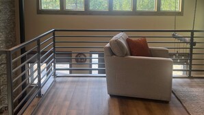 A spacious loft bedroom with a high ceiling, large windows, a ceiling fan, and a modern sofa. - Newer 3-bedroom cabin in fantastic Two Rivers North, free WiFi (Crescent Lake)