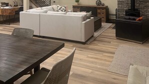 A modern living room with a sofa, a dining table, a TV mounted on the wall, and a fireplace. - Newer 3-bedroom cabin in fantastic Two Rivers North, free WiFi (Crescent Lake)