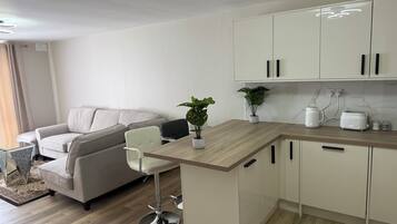 Une cuisine moderne avec un plan de travail en bois, des meubles blancs et un coin repas comprenant un canapé et des chaises.