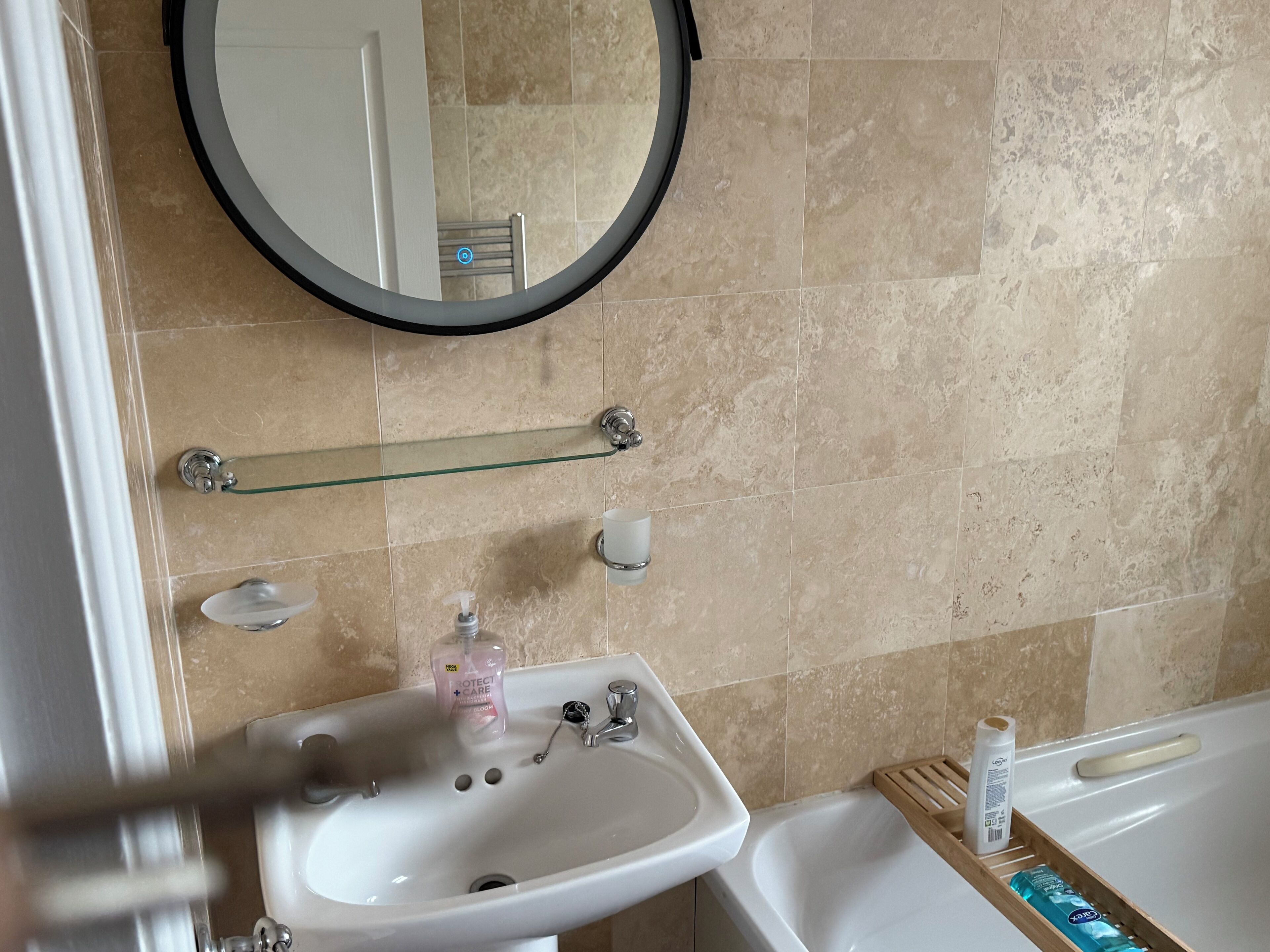 Un baño con lavamanos blanco, espejo y bañera.