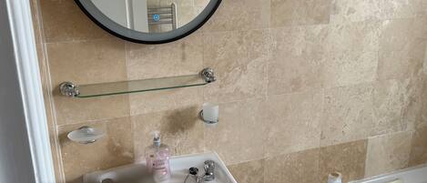 Un baño con lavamanos blanco, espejo y bañera.