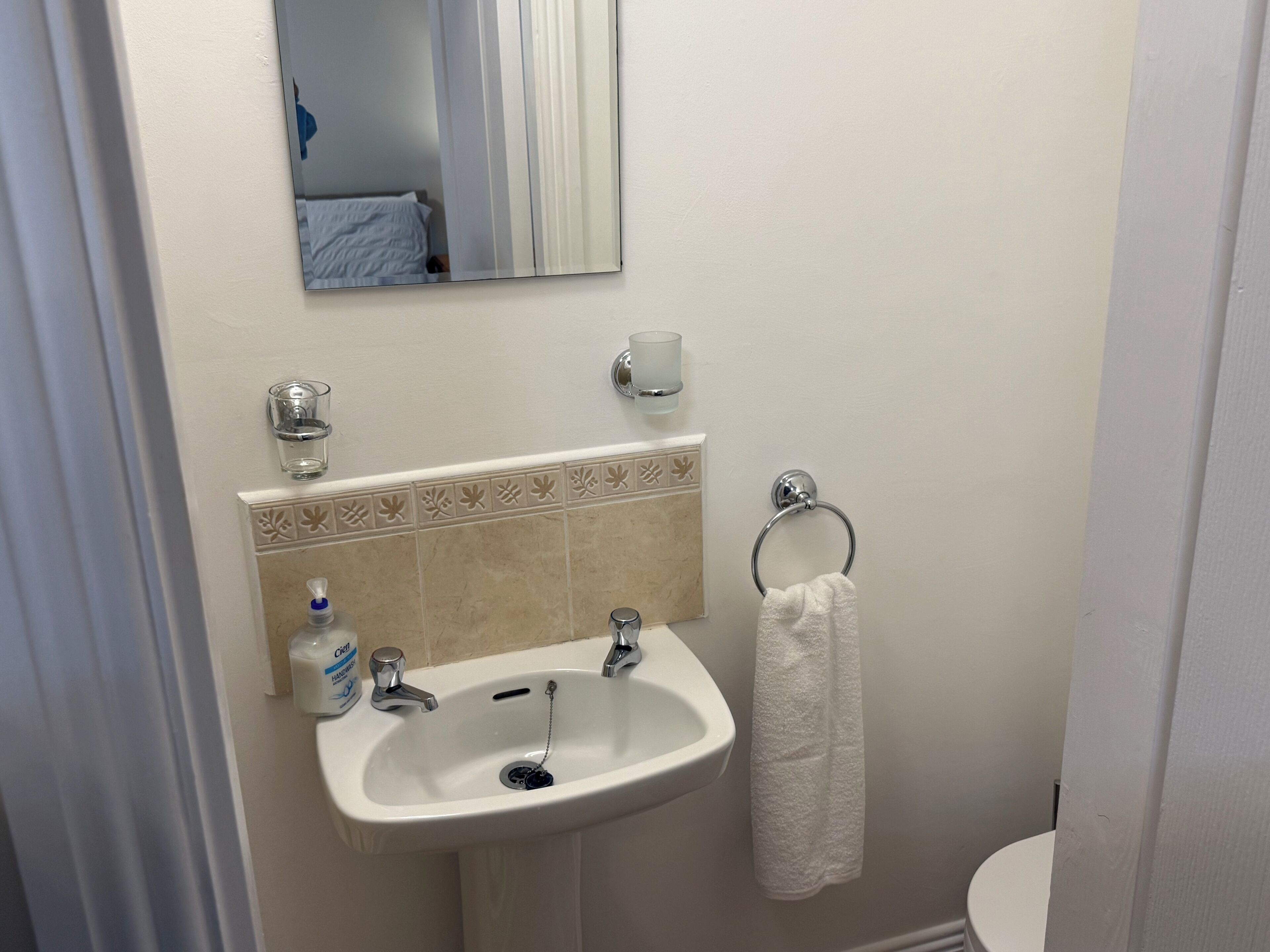 Un baño con un lavamanos blanco, un espejo, un tocaderecados y un inodoro.