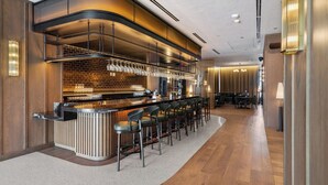 Un moderno bar con una barra curva, varios taburetes y un fondo de pared de ladrillo.