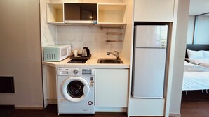Eine kleine Küchenzeile mit Waschmaschine, Mikrowelle, Spüle und Kühlschrank.