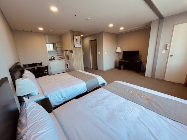 A hotel room with two beds, a desk, a TV, a washing machine, and a kitchenette. - Yongin Triny Hotel (Yongin)