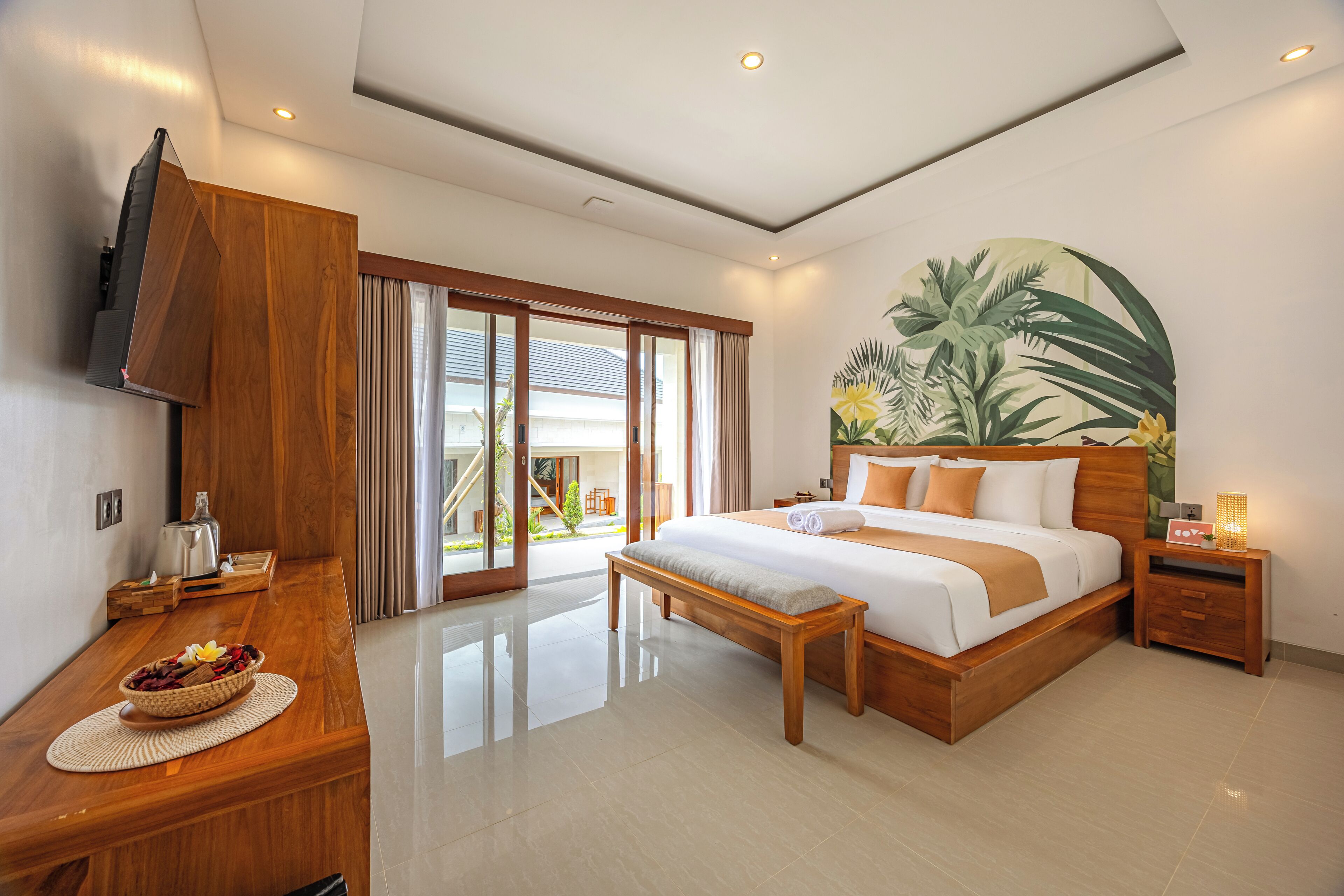 Een moderne hotelkamer met een groot bed, houten meubels, een flatscreen televisie en uitzicht op het omliggende landschap.