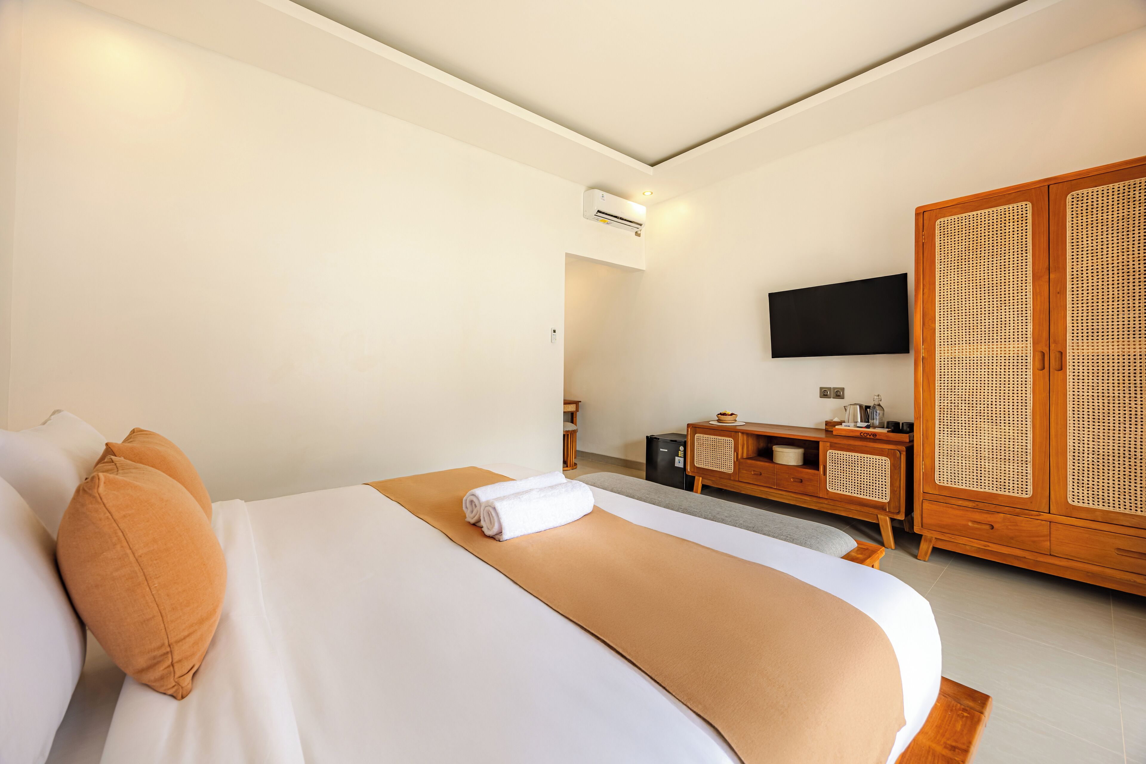 Habitación de hotel con cama, un armario de madera, un televisor y una pequeña zona de kitchenette.