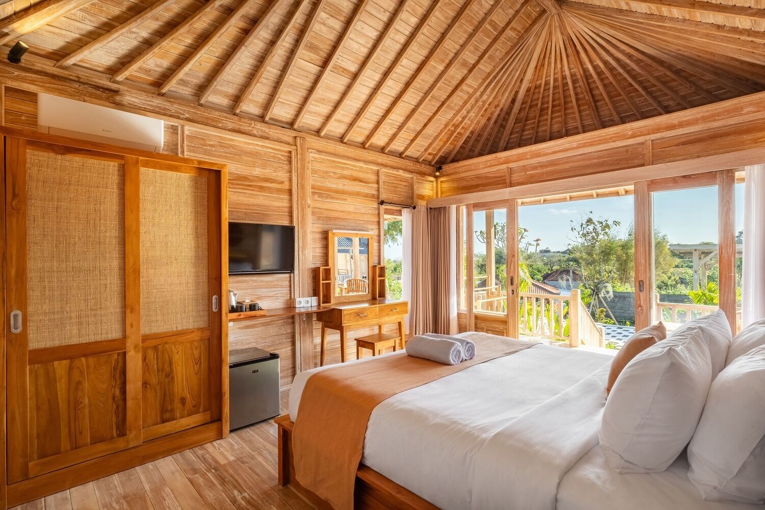 A wooden room with a bed, TV, and a desk.