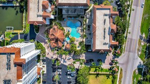 An aerial view of a hotel with a central swimming pool, multiple guest rooms, and a parking area. - Windward at Regatta - Modern vacation destination! (Naples)