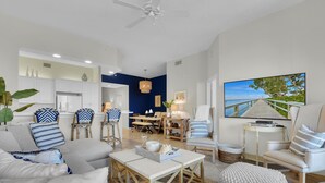 A modern living room with a sofa, armchairs, a coffee table, and a dining area. - Windward at Regatta - Modern vacation destination! (Naples)
