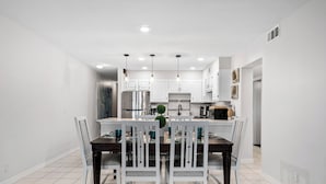 A modern kitchen with white cabinets, a central island, and pendant lighting.