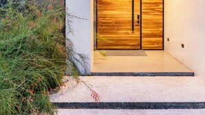 A modern house with a wooden door and a stone wall. - Villa Bosque (La Fortuna)