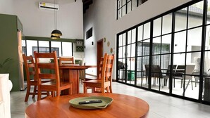 A dining area with a round wooden table, chairs, and a remote control on the table.