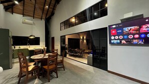 A spacious dining area with a high ceiling and a modern kitchen in the background.