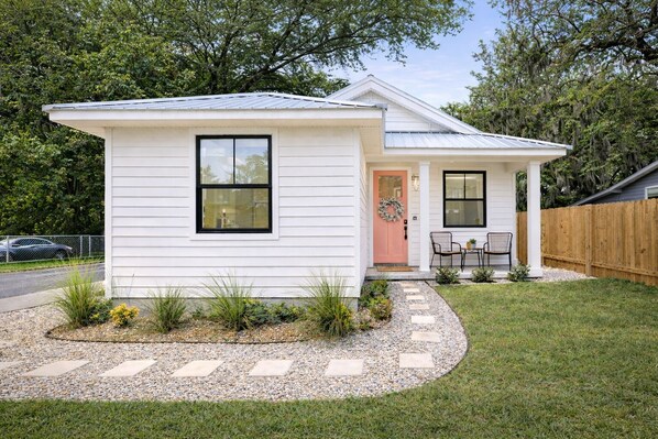 Une maison de plain-pied avec un porche à l’avant, un petit jardin et une clôture en bois.