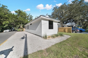 Une maison mobile de plain-pied, dotée d’un petit porche, d’une allée en gravier et d’une clôture en bois.