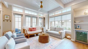 A spacious living room with a large window, a fireplace, and a ceiling fan. - Resort Pools, Golf Cart Boardwalk to the Beach, Pet Friendly (Port Aransas)