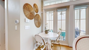 A dining area with a round table, white chairs, and a decorative wall piece. - Resort Pools, Golf Cart Boardwalk to the Beach, Pet Friendly (Port Aransas)