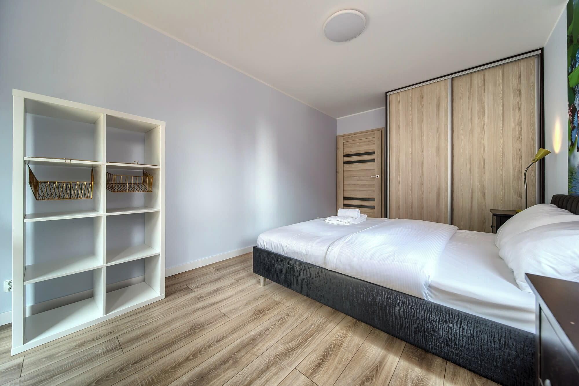 A bedroom with a bed, a wardrobe, and a built-in shelving unit.