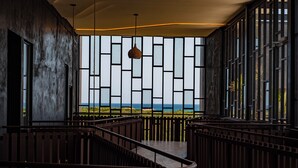 Ein modernes Interieur mit einer Treppe, großen Fenstern mit Meerblick und einer hängenden Pendelleuchte.