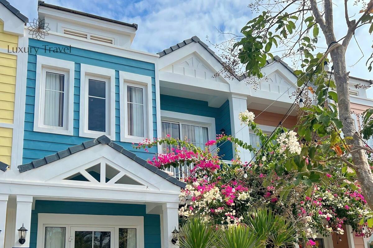 A two-story house with a blue and white exterior, a front door with glass panels, and a small porch area.