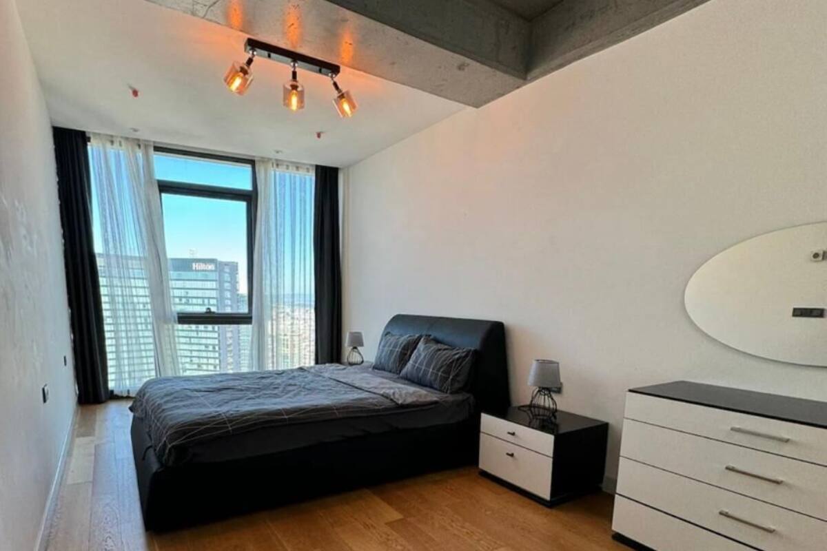 Une chambre à coucher moderne avec un grand lit, une commode et une table de chevet.