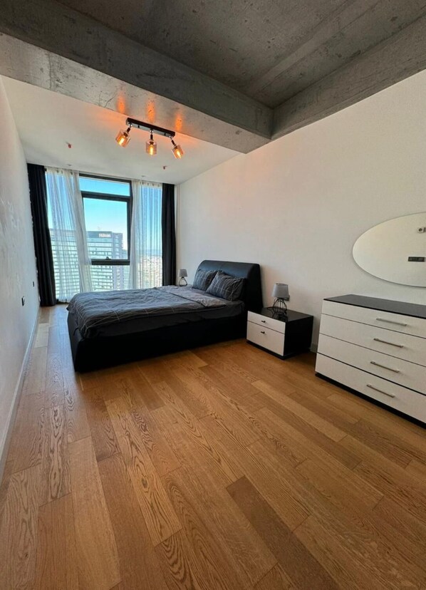 A modern bedroom with a large bed, a dresser, and a nightstand. - Sinpas Queen Bomonti Residence By Bondy (Istanbul)