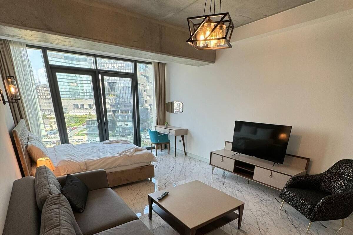Un salon moderne comprenant un canapé, une table basse, un téléviseur et un bureau.