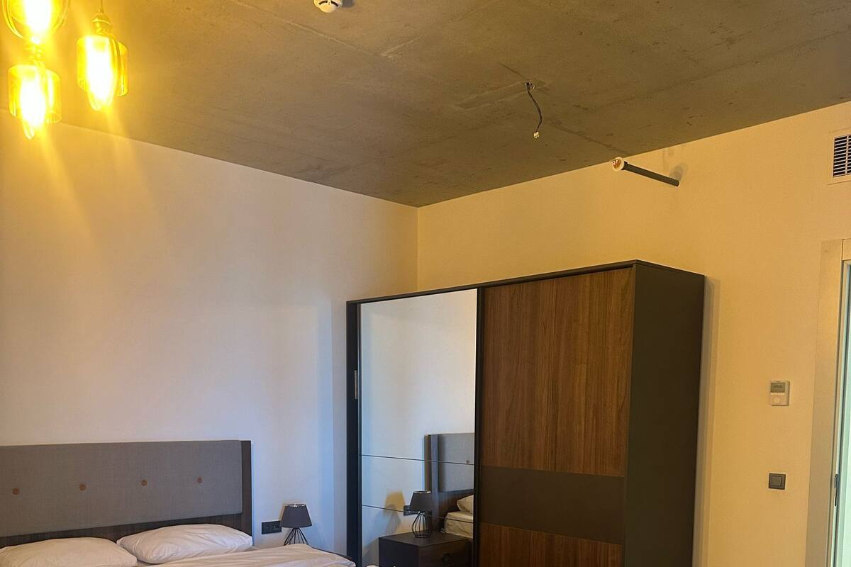 Une chambre d’hôtel moderne avec un grand lit, un plancher en bois, un bureau et un miroir.