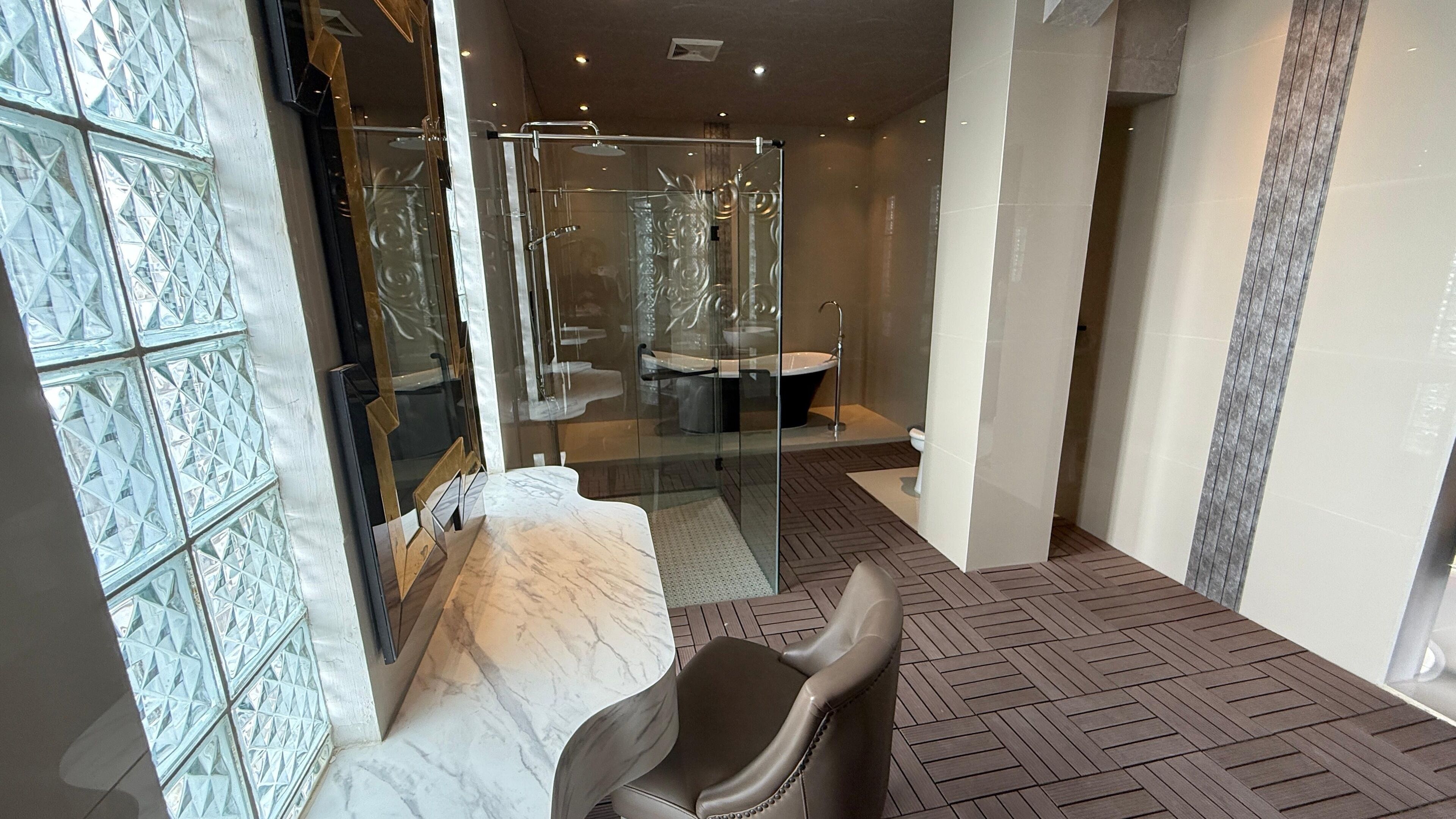 Une salle de bain moderne dotée d’une douche à parois de verre, d’un comptoir en marbre et d’un sol à motifs en chevrons.