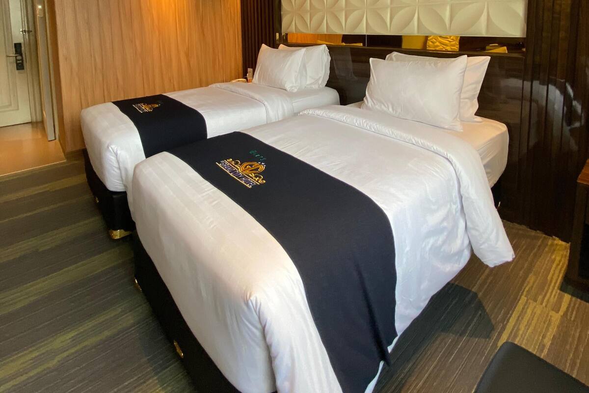 Une chambre d’hôtel avec un lit double, un plafond en bois et un panneau mural texturé.
