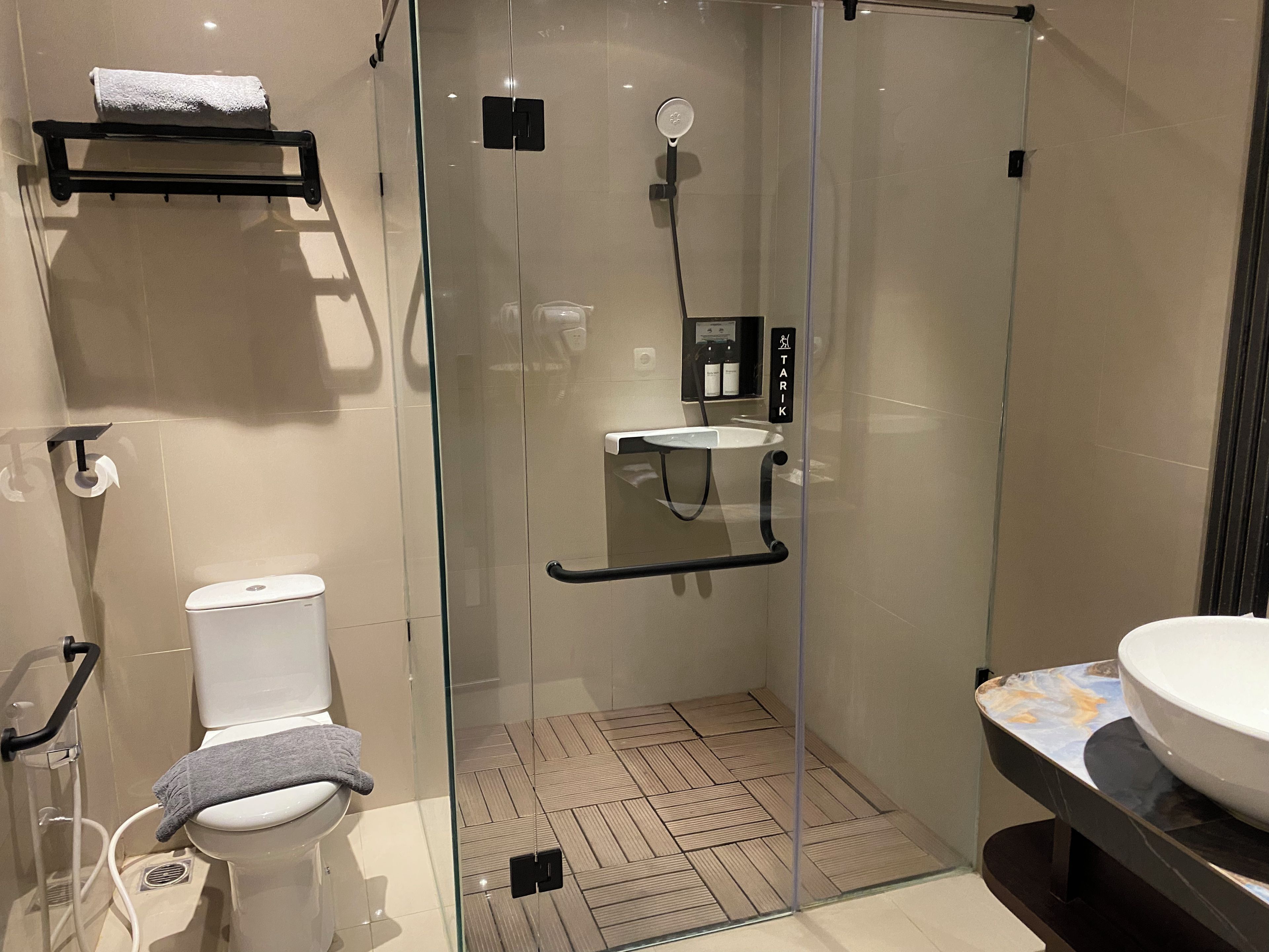A modern bathroom with a glass-enclosed shower, a toilet, and a sink with a marble countertop.