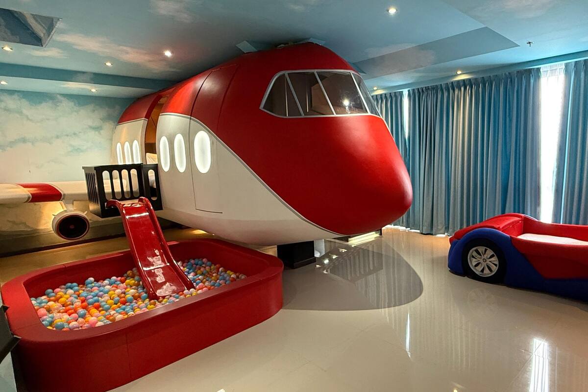 Un espace de jeux avec un avion rouge et blanc, une piscine à balles et une voiture jouet.
