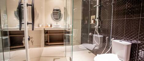 Un bany modern amb dutxa tancada per vidre, un vàter i un lavabo amb mirall.