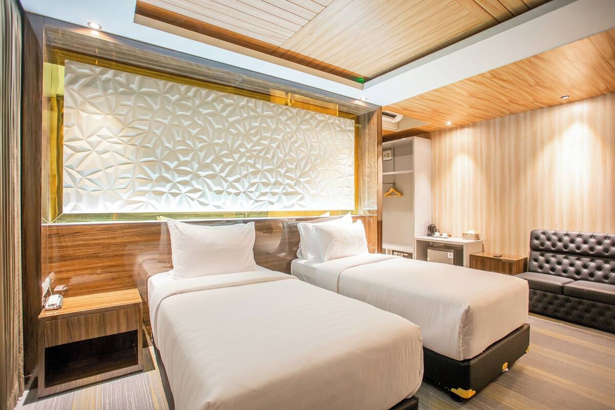 Une chambre d’hôtel avec deux lits, un canapé, un bureau et une armoire.