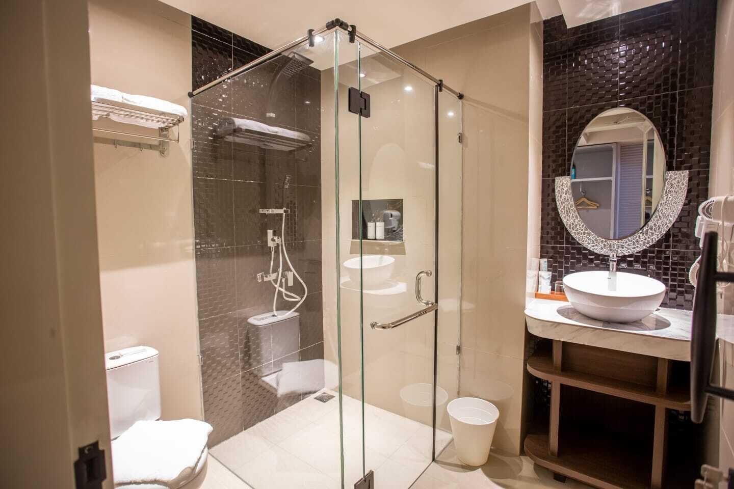 A modern bathroom with a glass-enclosed shower, a white sink, and a mirror with a decorative frame.