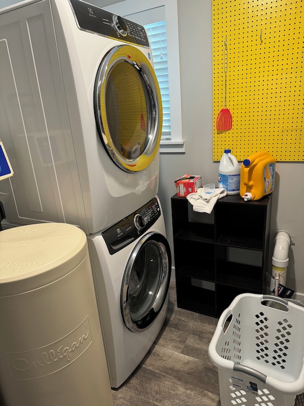 A compact laundry area with a front-loading washing machine, a dryer, a yellow pegboard, and a laundry basket. - Wildcat Ridge,gorgeous,great location,modern,sleeps 9 (Manhattan)