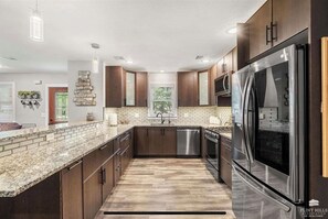 A modern kitchen with granite countertops, stainless steel appliances, and dark wooden cabinets. - Wildcat Ridge,gorgeous,great location,modern,sleeps 9 (Manhattan)