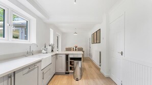 Una cuina moderna amb armaris blancs, un rentapeus d'acer inoxidable i un forn encastrat.
