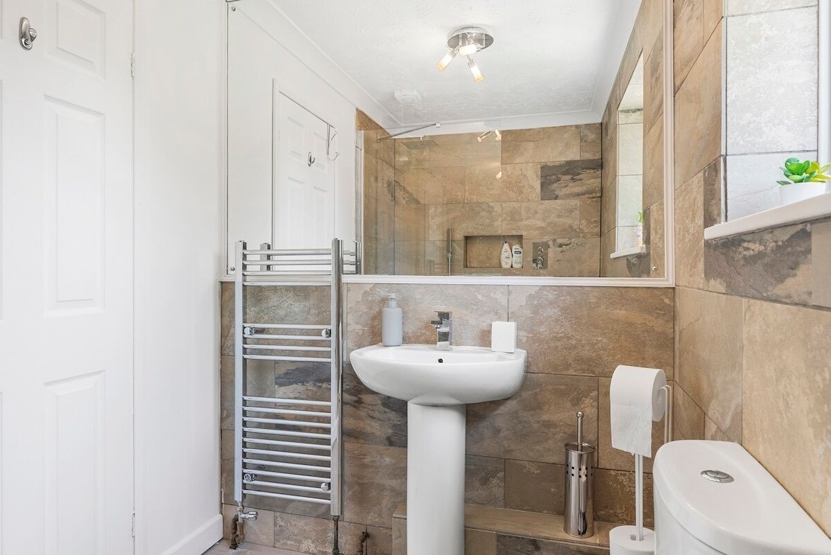A bathroom with a white sink, a towel rack, and a toilet.