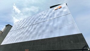 Un bâtiment moderne doté d’une grande façade réfléchissante et d’un panneau bien visible indiquant « PARKING » à sa base.