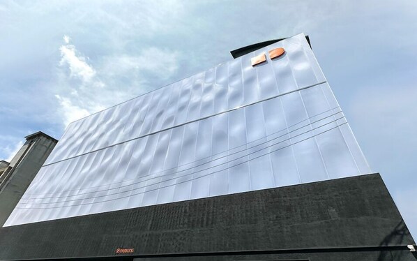 Un edificio moderno con una amplia fachada reflectante y un cartel grande que dice 'PARKING' en la base.