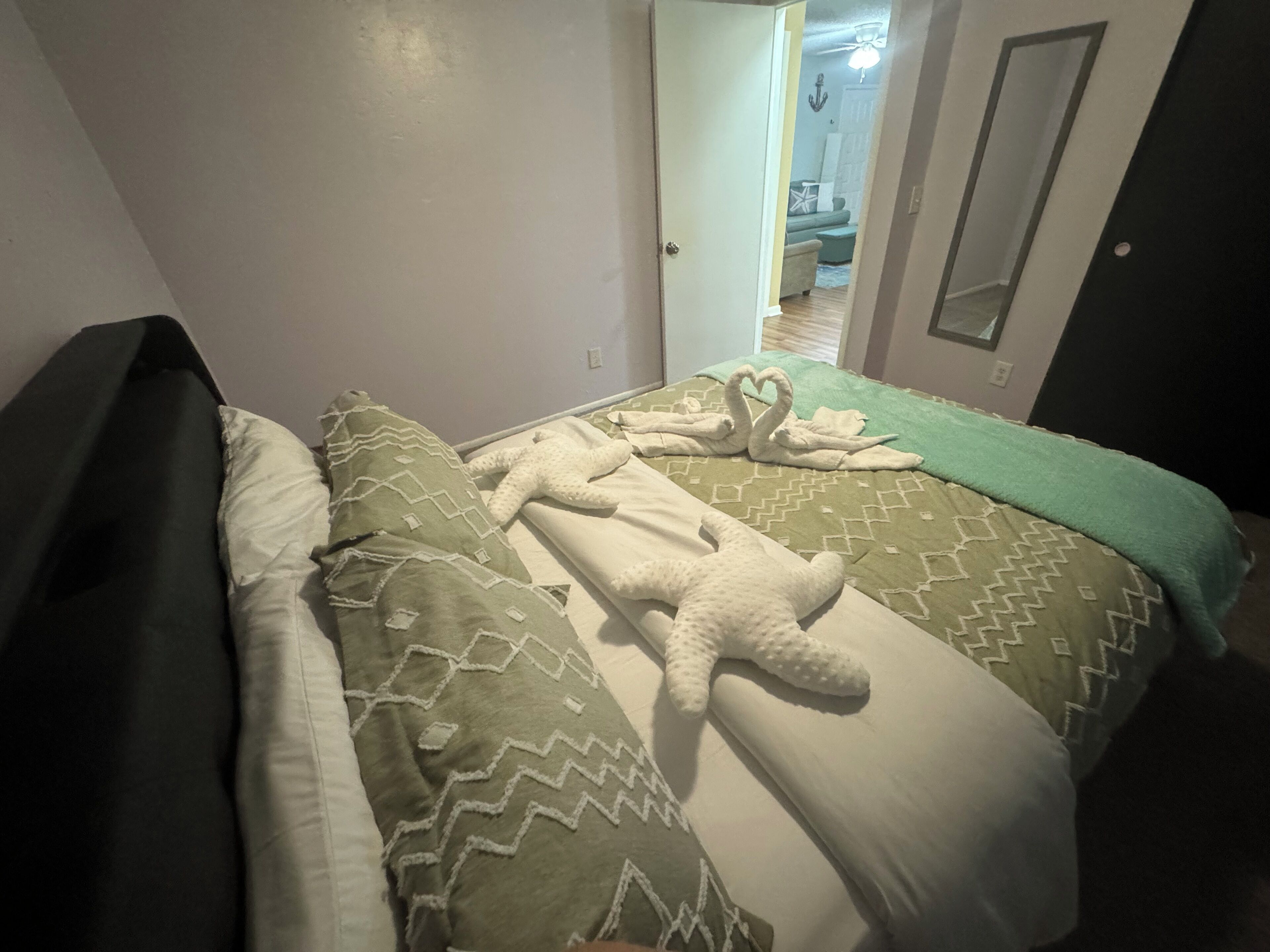 Une chambre à coucher avec un lit, des oreillers et une couverture. Une porte donne accès à une autre pièce.